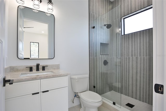 bathroom with a shower with door, vanity, and toilet