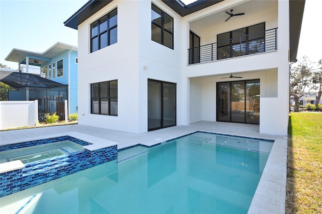 rear view of property featuring a patio, a balcony, ceiling fan, and a pool with hot tub