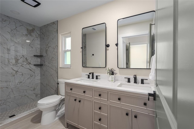 bathroom with vanity, toilet, and a tile shower