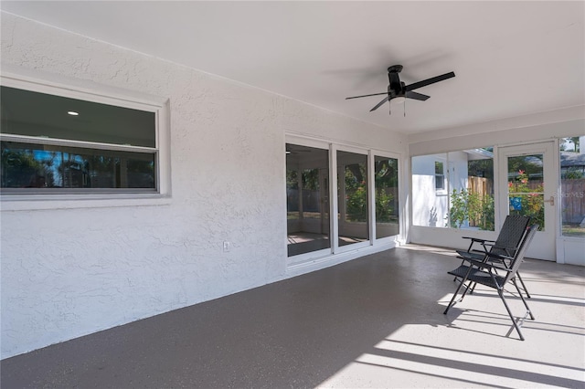 unfurnished sunroom featuring ceiling fan