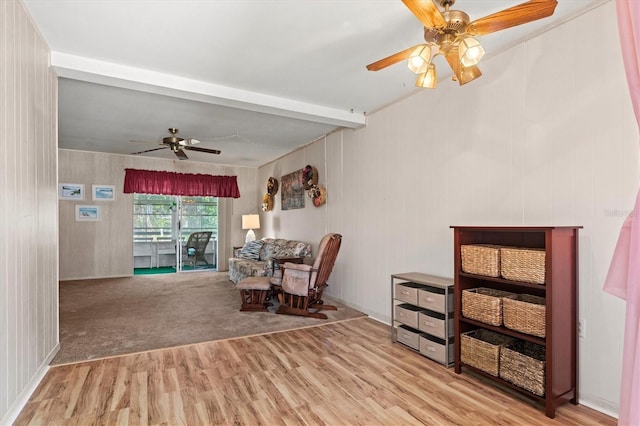 living area featuring beamed ceiling, ceiling fan, and light hardwood / wood-style flooring