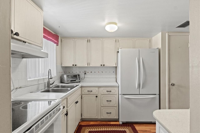 kitchen with tasteful backsplash, white appliances, light hardwood / wood-style floors, and sink