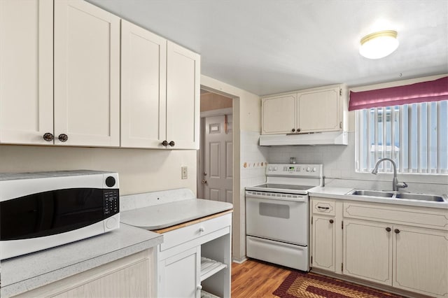 kitchen featuring white appliances, sink, light hardwood / wood-style flooring, and backsplash