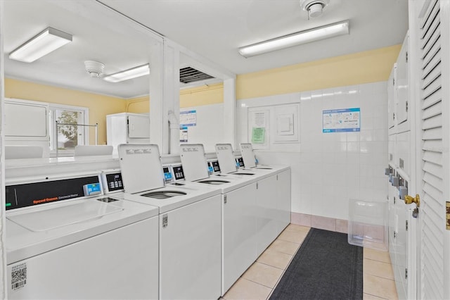 clothes washing area featuring stacked washing maching and dryer, washer and dryer, and light tile patterned floors