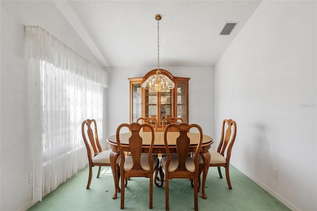 carpeted dining room featuring an inviting chandelier, lofted ceiling, and a textured ceiling