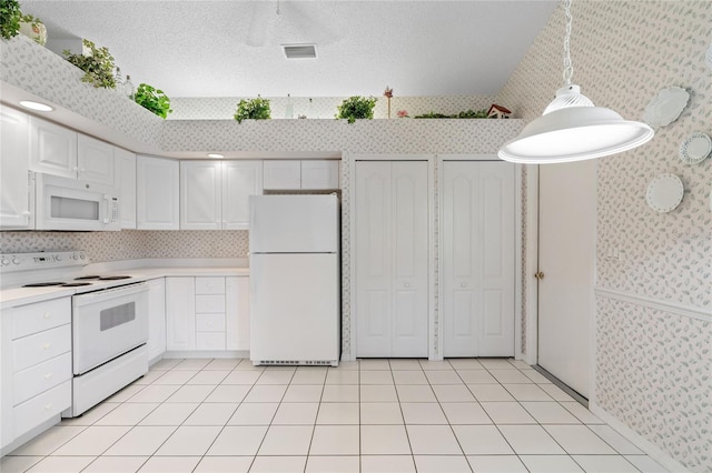 kitchen featuring light tile patterned flooring, pendant lighting, white cabinets, white appliances, and a textured ceiling