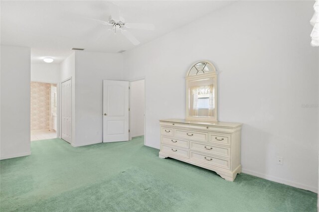 unfurnished bedroom with ceiling fan, light colored carpet, and connected bathroom