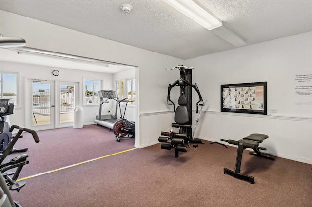 workout area featuring carpet floors, french doors, and a textured ceiling