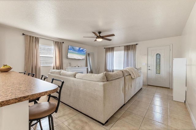 living room with light tile patterned flooring, a wealth of natural light, a textured ceiling, and ceiling fan