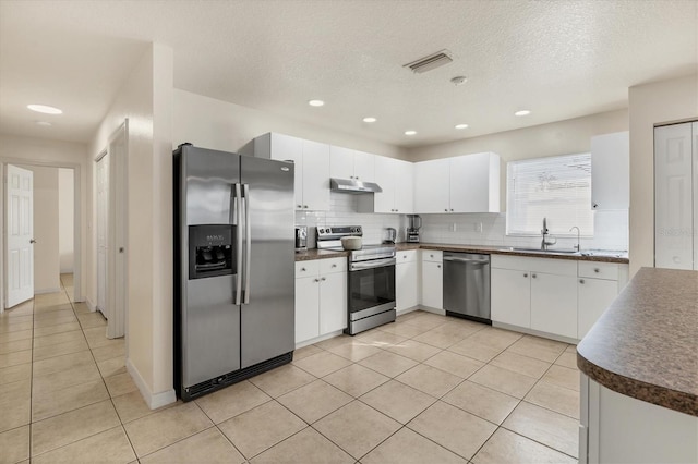 kitchen with light tile patterned floors, stainless steel appliances, sink, and white cabinets