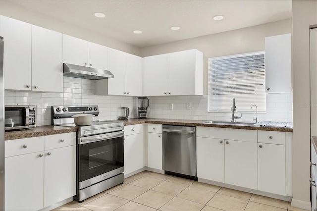 kitchen with sink, light tile patterned floors, stainless steel appliances, tasteful backsplash, and white cabinets