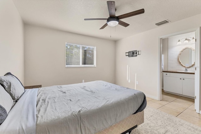 bedroom featuring light tile patterned flooring, sink, ensuite bath, a textured ceiling, and ceiling fan