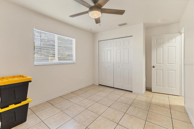 unfurnished bedroom featuring light tile patterned flooring, ceiling fan, and a closet