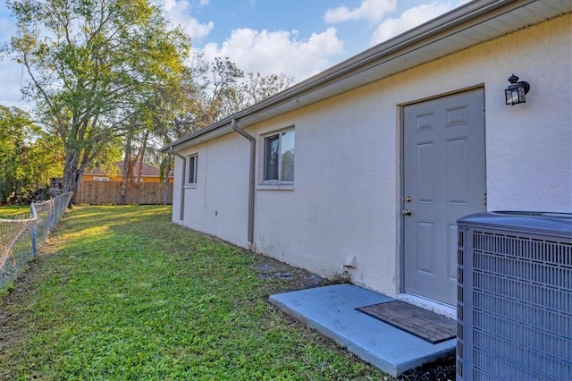 doorway to property featuring cooling unit and a lawn