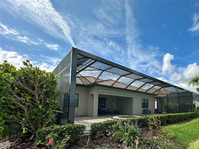 7760 Grande Shores Dr, Sarasota, FL 34240 - back of house with stucco siding, a patio, glass enclosure, and a tile roof