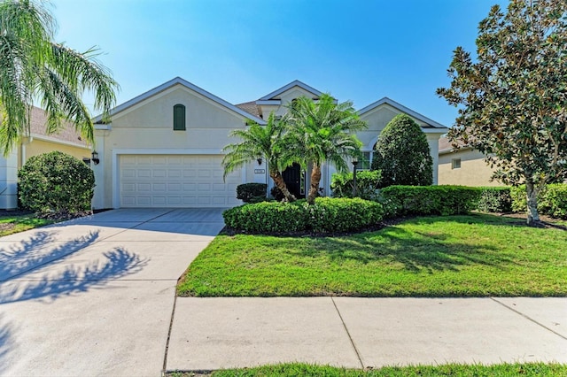 view of front facade with a front yard, an attached garage, driveway, and stucco siding