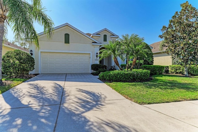 view of front facade with a front lawn, a garage, driveway, and stucco siding