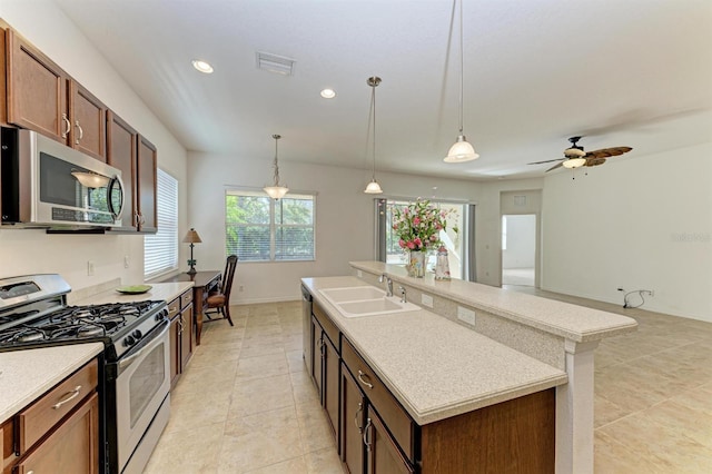 kitchen featuring visible vents, an island with sink, a sink, decorative light fixtures, and appliances with stainless steel finishes