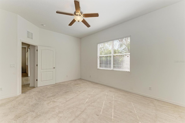 spare room with baseboards, a ceiling fan, visible vents, and light carpet