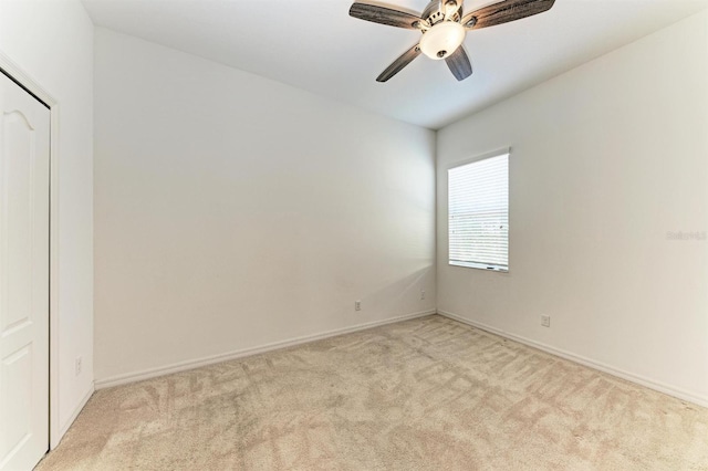 spare room with light carpet, baseboards, and a ceiling fan