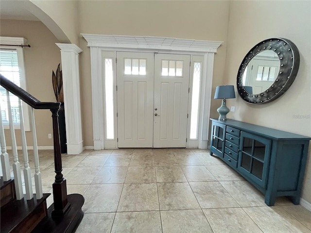 foyer featuring decorative columns and light tile patterned floors