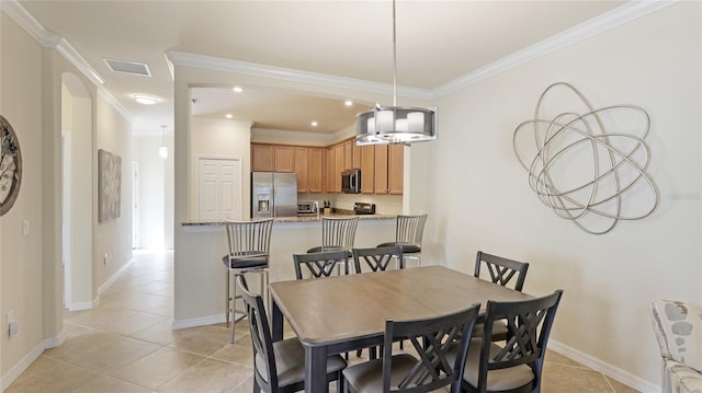 dining space featuring ornamental molding and light tile patterned flooring