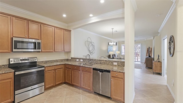 kitchen with sink, light tile patterned floors, appliances with stainless steel finishes, ornamental molding, and stone countertops