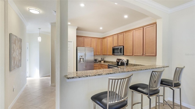 kitchen with stone countertops, a kitchen bar, ornamental molding, and appliances with stainless steel finishes