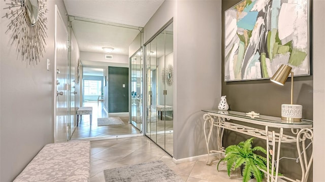 corridor with a textured ceiling and light tile patterned floors