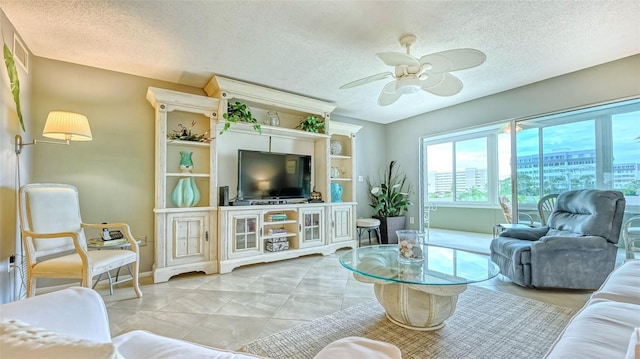 living room featuring light tile patterned flooring, ceiling fan, and a textured ceiling