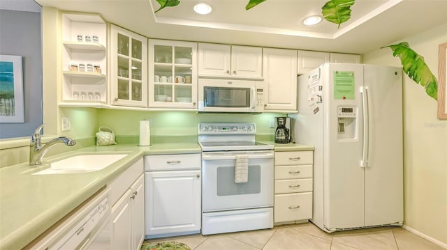 kitchen featuring white appliances, a tray ceiling, sink, and white cabinets