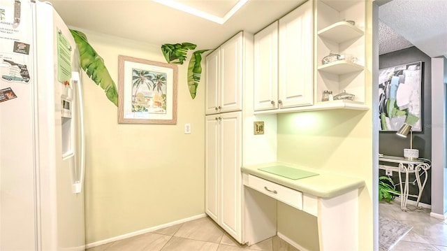 kitchen with white cabinetry, white fridge with ice dispenser, a textured ceiling, and light tile patterned floors