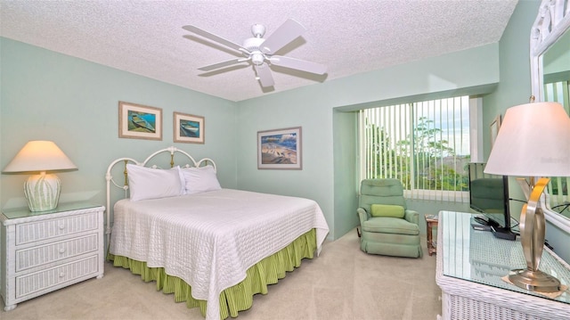 bedroom with ceiling fan, light colored carpet, and a textured ceiling