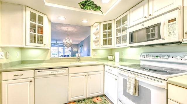 kitchen with sink, white appliances, white cabinetry, a notable chandelier, and decorative light fixtures