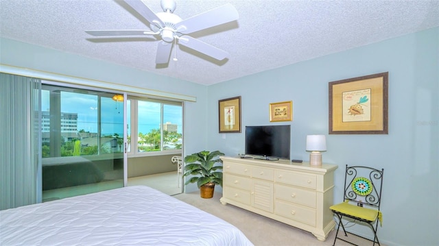 bedroom with ceiling fan, access to outside, light colored carpet, and a textured ceiling