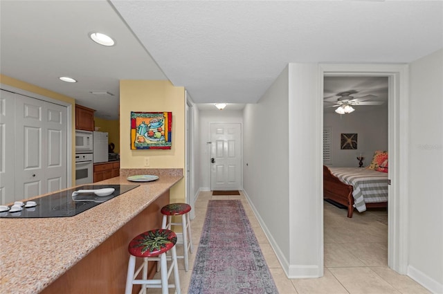 kitchen with ceiling fan, white appliances, a breakfast bar area, and light tile patterned floors