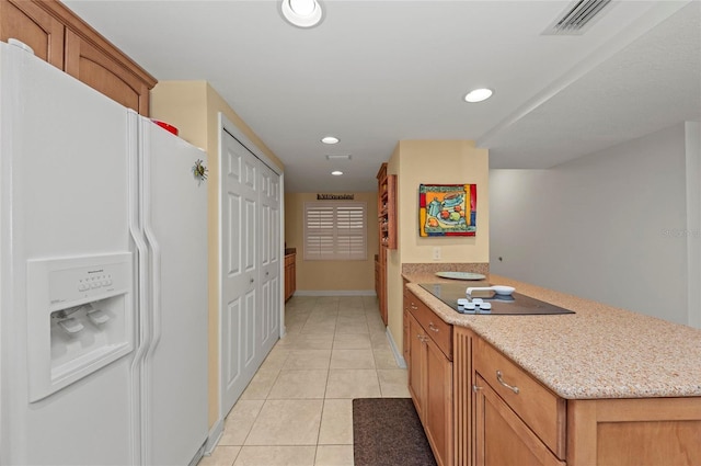 kitchen featuring light stone counters, light tile patterned floors, white fridge with ice dispenser, and black electric stovetop