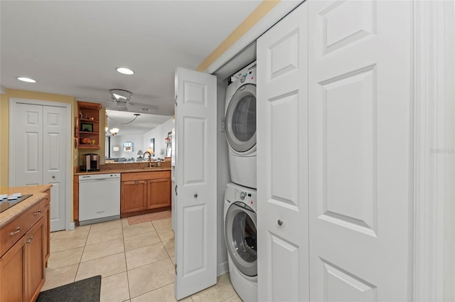 laundry area featuring light tile patterned floors, sink, and stacked washing maching and dryer