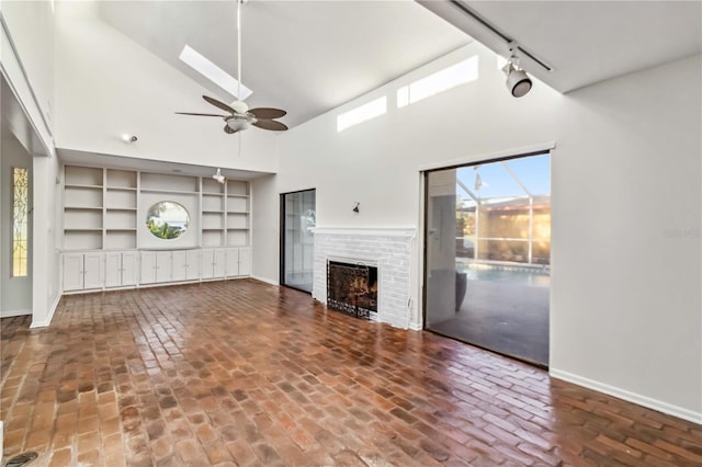 2375 Riverwood Pines Dr, Sarasota, FL 34231 - unfurnished living room featuring ceiling fan, a fireplace, rail lighting, and a high ceiling