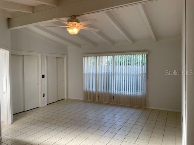 spare room featuring lofted ceiling with beams, light tile patterned floors, and a ceiling fan