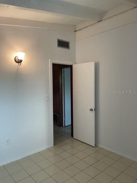 unfurnished room with vaulted ceiling with beams, light tile patterned floors, visible vents, and baseboards