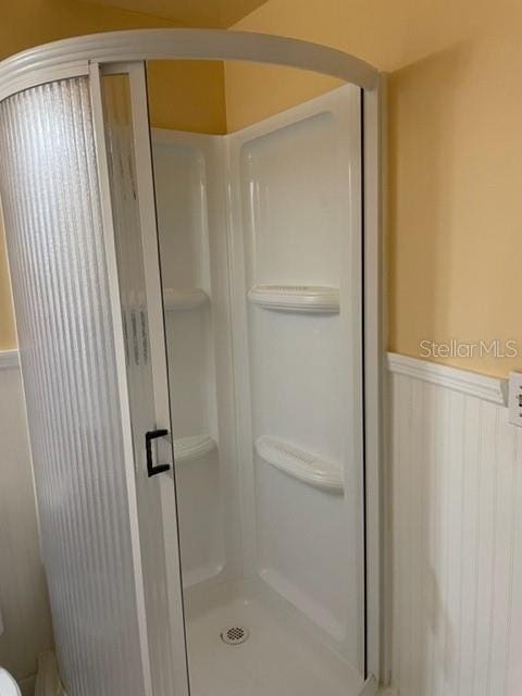 bathroom with wainscoting and a shower stall