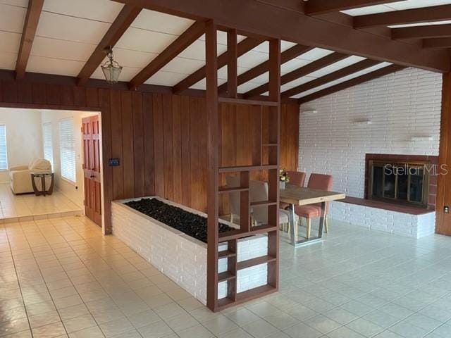 interior space featuring a fireplace, wood walls, and lofted ceiling with beams