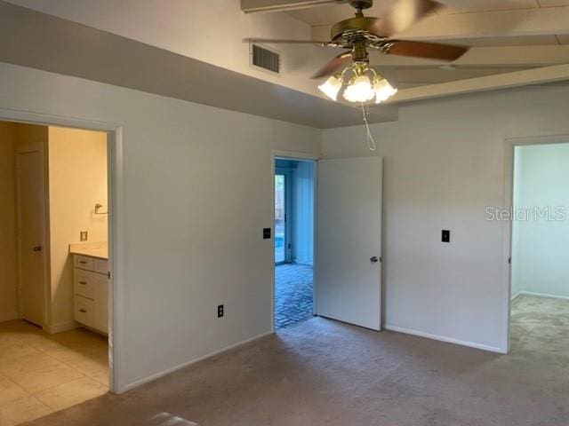 unfurnished bedroom featuring beamed ceiling, ensuite bath, visible vents, and light colored carpet