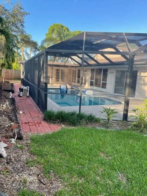 view of swimming pool with a lanai, a yard, a fenced in pool, and a patio