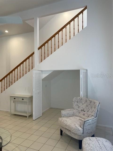 living area with light tile patterned floors, baseboards, stairs, a high ceiling, and recessed lighting