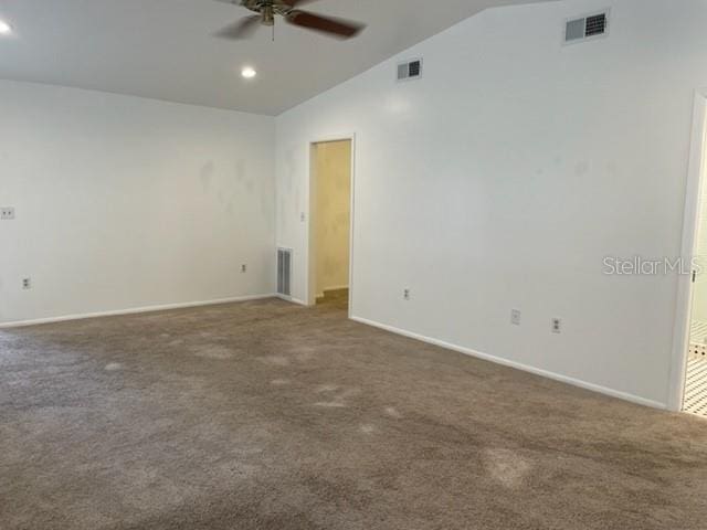 empty room featuring vaulted ceiling, visible vents, dark carpet, and ceiling fan