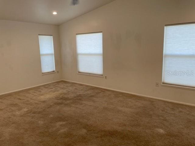 empty room with carpet floors, baseboards, and vaulted ceiling