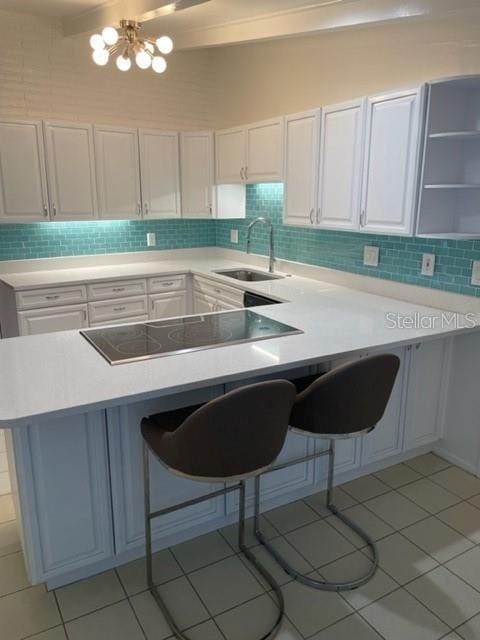 kitchen with a breakfast bar, white cabinets, a sink, and light countertops