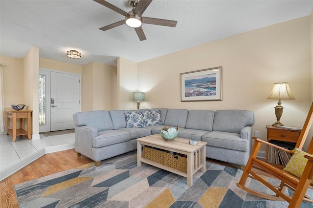 living room with ceiling fan, a textured ceiling, and light hardwood / wood-style floors